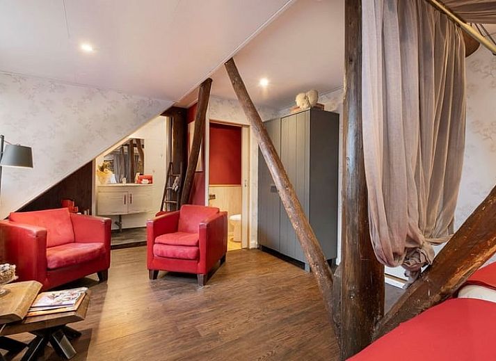 Gezellige slaapkamer in Vakantiehuisje in Stieltjeskanaal, Drenthe met hemelbed en warme inrichting.