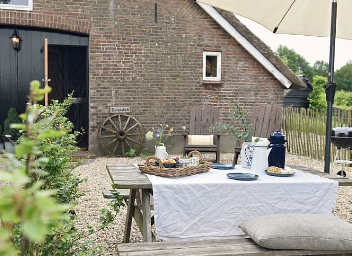 Speeltuin bij Huisje in Oosterwolde, Veluwe, Gelderland met houten speeltoestellen en groen uitzicht.