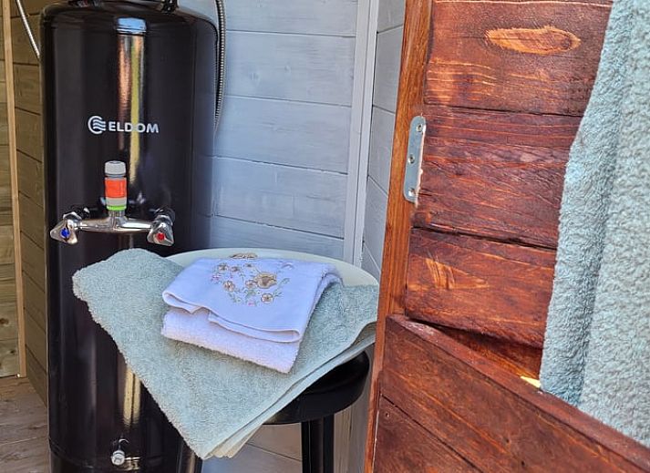 Charmanter Aussenbereich des Ferienhauses in Overdinkel, Twente, mit Holzterrasse und Gartenmoebeln.