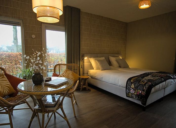 Sunny facade of Holiday Home in Oldenzaal, Twente, with solar panels and green hedge for lasting charm.