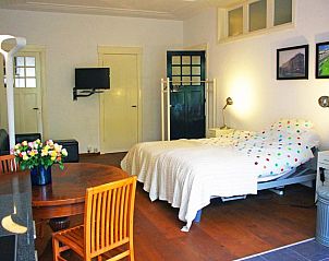 Ruime slaapkamer in Bed & Breakfast Walenburg, Rotterdam, met houten vloer.