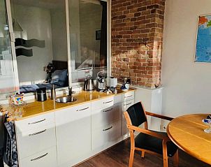 Moderne kitchenette in Imagine My B&B Rotterdam met bakstenen muur en houten accenten.