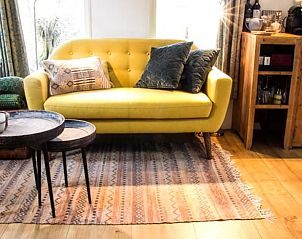 Gezellige binnenruimte in Vakantiehuis in Diever, Zuidwest Drenthe, met een comfortabele gele bank en stijlvolle inrichting.