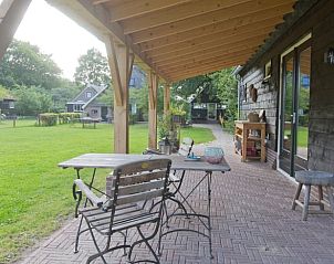Ruime veranda van Vakantiehuis in Diever, Zuidwest Drenthe, met zitgelegenheid en uitzicht op het groene landschap.