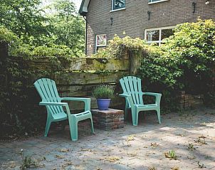 Buitenruimte in Vakantiehuisje in Hoenderloo, Veluwe, met gezellige zitplaatsen en groene omgeving.