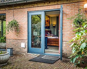 Charmante entree van studio REE, bed and breakfast in Wekerom, Veluwe met groene planten en bakstenen muur.
