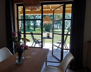 Open deuren naar het terras in Vakantiehuis in Stroe, Veluwe, met bloemen.