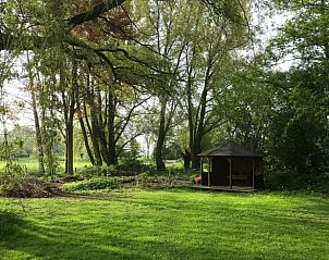 Ruime tuin met houten prieel in Vakantiehuis in Oene, Veluwe, perfect voor ontspanning in de natuur van Gelderland.