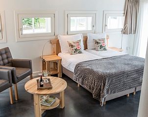 Gezellige zithoek naast het bed in Notterveld B&B, Notter, Twente, met uitzicht op de groene omgeving.