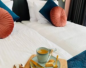 Stijlvolle slaapkamer in B&B Duinhuys, Walcheren met luxe beddengoed en warme kleuren.