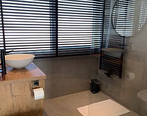 Ruime badkamer in B&B Duinhuys, Zeeland met glazen douchewand en natuurlijke lichtinval.